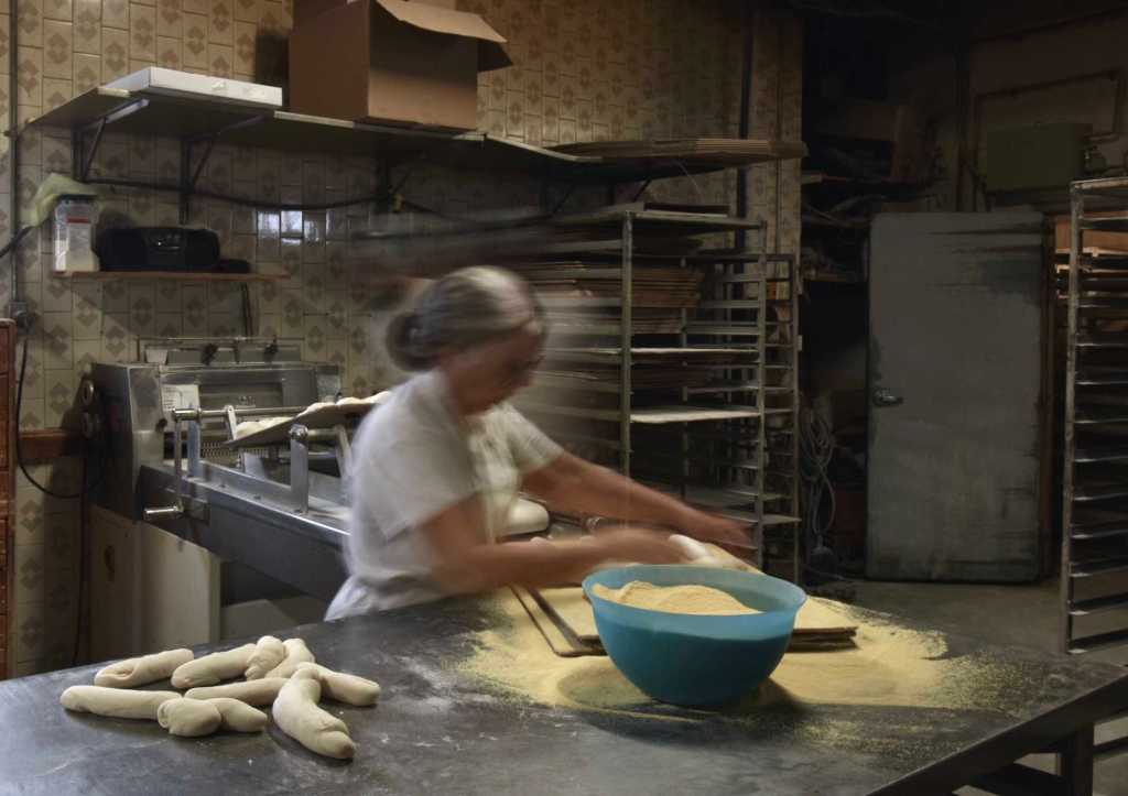 A woman manually creating dough from scratch to be used for baking bread.